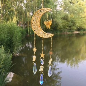 Close-up of golden moon sun catcher with yellow crystals and prisms by a lake