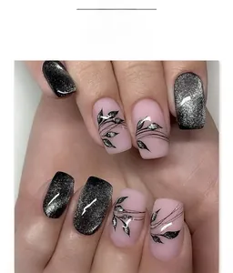 Detail of black cat eye press-on nails with hand-painted leaf patterns on square oval tips