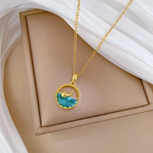 Elegant gold whale necklace with blue crystals on a beige jewelry box with soft fabric