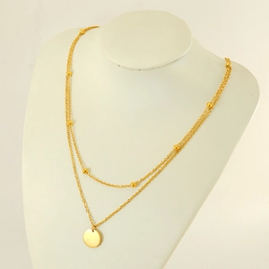 Double layered gold necklace featuring bead chain and smooth round pendant on mannequin