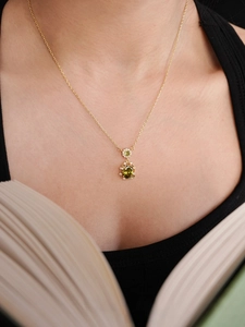 Close-up of elegant gold necklace with green oval pendant worn on a model neck