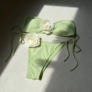 Detail of light green bikini featuring 3D white rose ornaments and side tie bottoms