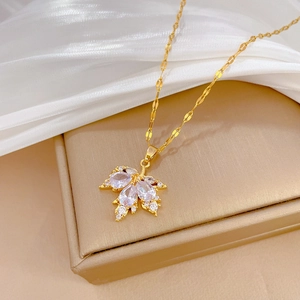 Macro detail of gold maple leaf pendant with zircon inlay on luxury jewelry stand