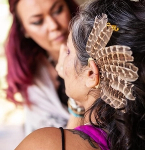 Detailed view of bohemian ear cuff featuring natural brown striped feathers and brass metal