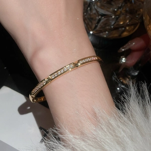 Close-up of 18k gold plated bangle with sparkling zircons on a wrist at night