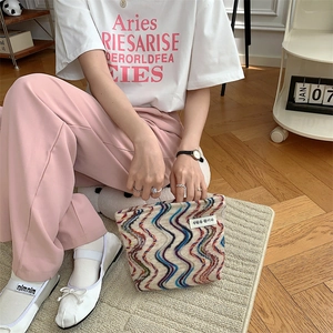 Close-up of rainbow knit canvas makeup bag with wave texture and woven brand label