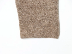 Detailed macro view of soft knit texture and ribbed cuff on a camel wool sweater