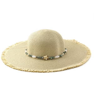 Detail of wide brim straw hat with bohemian shell bead band and fringe edges