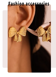 Close-up of golden brushed bow earrings on model showing textured PVD finish