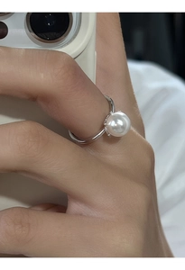 Dettaglio macro di un classico anello con perla e fascia argentata indossato sul dito