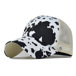 Detail of cow print trucker hat featuring black and white patterns with mesh panels