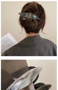 Macro detail of long acetate hair clip with gray marble texture and streamlined design