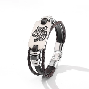 Detailansicht eines braunen geflochtenen Lederarmbands mit gravierter silberner Tigerkopfplatte