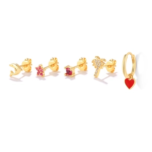 Detailed set of five gold earrings with dolphin, floral, and red heart charms on white background