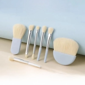 Detail of 6 mini portable makeup brushes with light blue handles and soft cream bristles