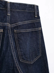 Détail de jean denim indigo foncé avec coutures orange contrastées et poche arrière précise