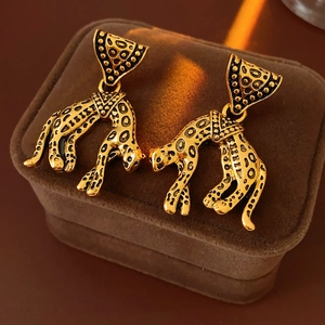 Macro view of vintage gold leopard earrings with black spots on a velvet box