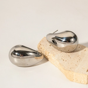 Macro shot of high-polish silver teardrop earrings on natural textured stone base
