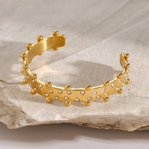 Detailed close-up of a gold 18k stainless steel C-shaped bangle with embedded rhinestones