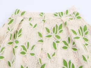 Détail d'une jupe en crochet beige avec broderie de feuilles vertes et zip invisible