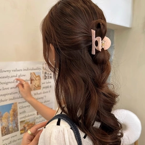 Pink marble acetate hair claw clip styling a half-up bun hairstyle on a female model