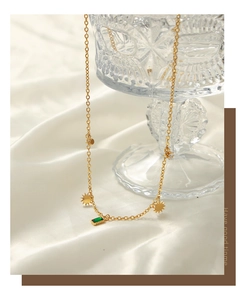 Detail of gold plated steel necklace featuring green rectangle zircon and sun charms