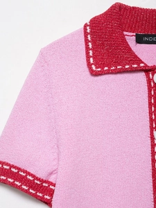 Detail of pink knit polo shirt featuring red contrast stitching and white dashed seams