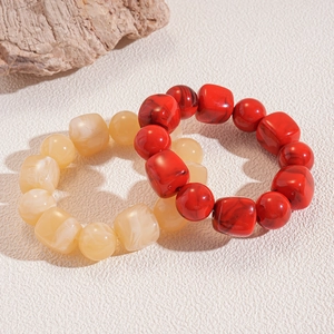 Macro shot of red and cream acrylic beaded bracelets with marble texture and round cubes