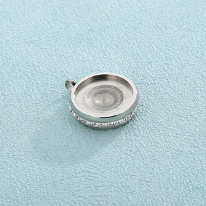 Macro shot of silver stainless steel round pendant base with textured edges and bail