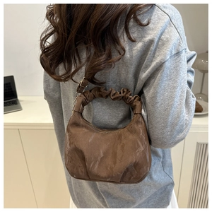 Detail of dark brown croissant bag with ruched handle and vintage leather texture