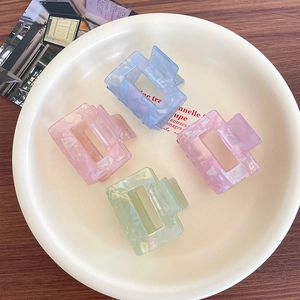 Rectangle acetate hair claws in pastel blue, pink, purple, and green on a white tray