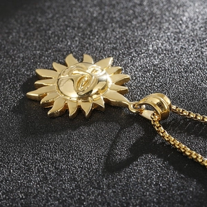Macro view of a 3D golden sun face pendant on a box chain with detailed engraving