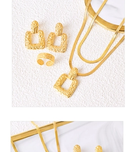 Macro view of textured gold jewelry set featuring earrings, necklace and ring on marble