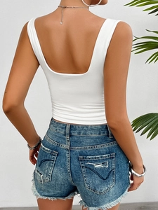 Détail d'un haut dos nu blanc ajusté Y2K avec short en jean bleu effiloché