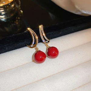 Detail of vintage gold earrings featuring sparkling crescents and glossy red beads