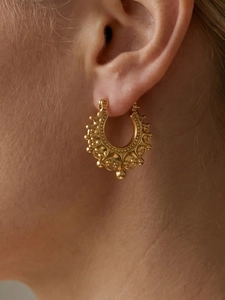 Detailed close-up of golden vintage hoop earrings with beaded edges and ornate textures