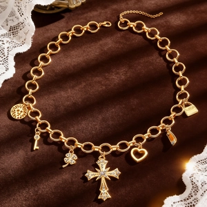 Detailed close-up of layered gold necklace with multiple charms on dark velvet