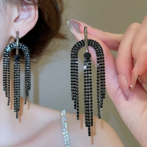 Détail de boucles d'oreilles à pampilles en strass noirs avec design demi-cercle