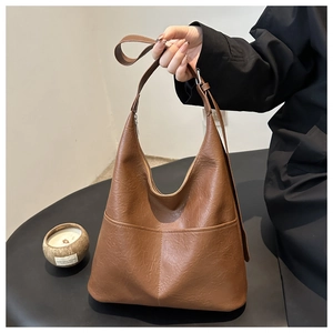 Chic brown leather tote bag held by model in a minimalist stylish indoor setting