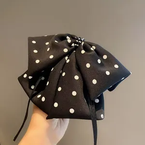 Detailed close-up of a black polka dot bow hair clip with black beads and silk ribbons