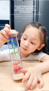 Close-up of a child playing with a wooden rainmaker tube toy for sensory development