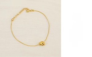 Detail shot of a minimalist gold chain bracelet featuring a 3D letter F pendant charm