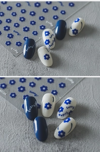 Close-up of 5D nail art stickers with blue flowers and Friday text on a textured surface