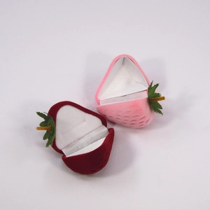 Detail of pink and red strawberry-shaped flocking ring boxes with soft green leaf accents
