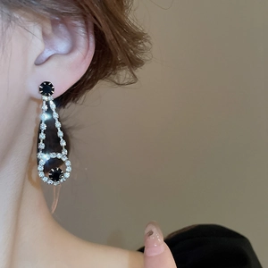 Detail of luxury teardrop fringe earrings with black stones and sparkling diamonds