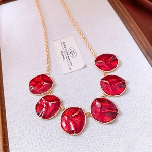 Detailed close-up of red enamel textured round pendants on a gold vintage chain necklace
