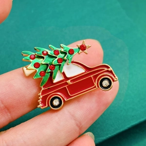 Macro detail of a red Christmas car brooch with a green rhinestone tree held by hand