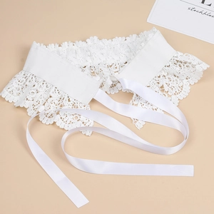 Detailed close-up of intricate white lace floral embroidery and silky satin ribbon ties
