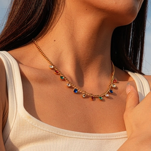 Detail of gold necklace featuring colorful round gemstones on model neck in natural light