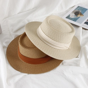 Flat lay of woven straw hats in cream and brown with elegant ribbon detail and stylish texture